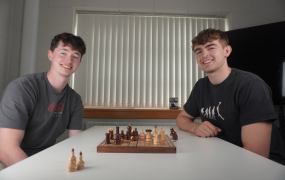 Two MIC students posing for a photo while playing a game of chess