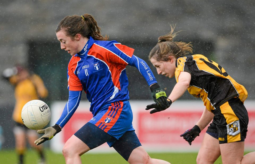A female Gaelic football player in Mary Immaculate College colours moving past a competitor in a match