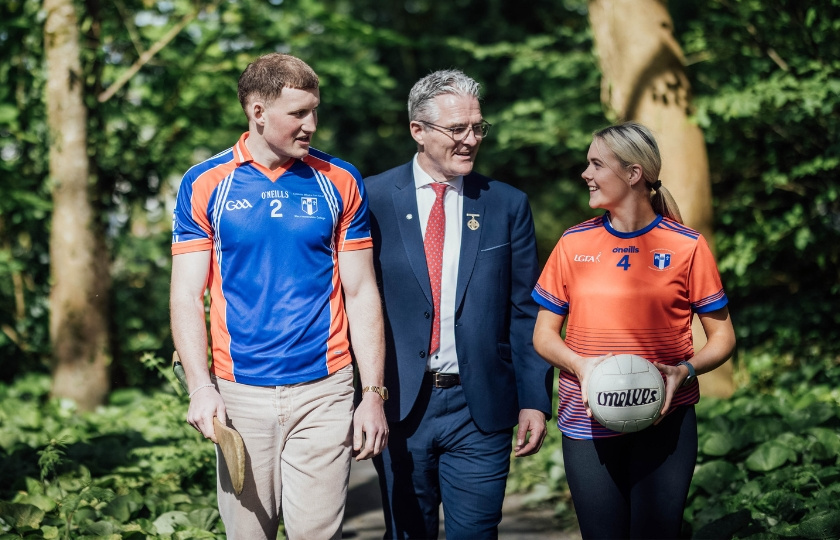 Male and female sport student walking with GAA President Jarlath Burns
