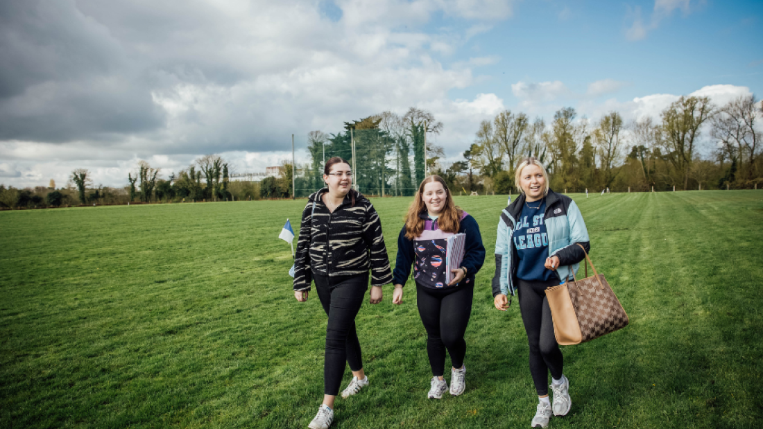 Three students walking next to the GAA pitch in MIC Thurles
