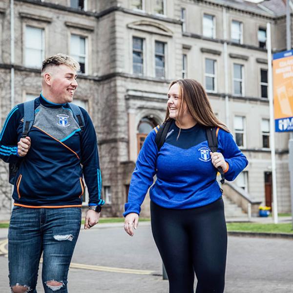 Two students walking together at the front of MIC main building.