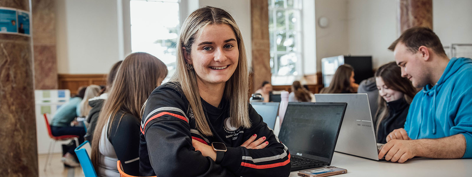 Female student sitting in canteen with laptop open on the table