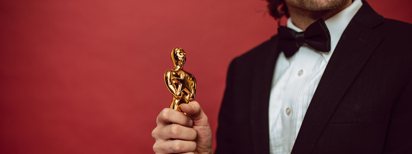 Man in tuxedo holding an Oscar statuette