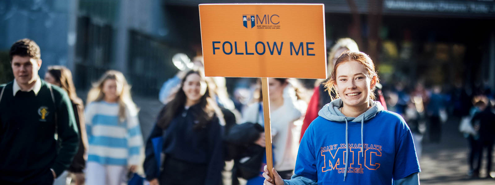 Female student carrying Follow Me signs leading a tour at MIC Limerick Campus.