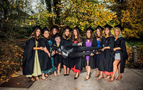 Male graduate being carried by a group of female graduates at MIC Graduation 2024