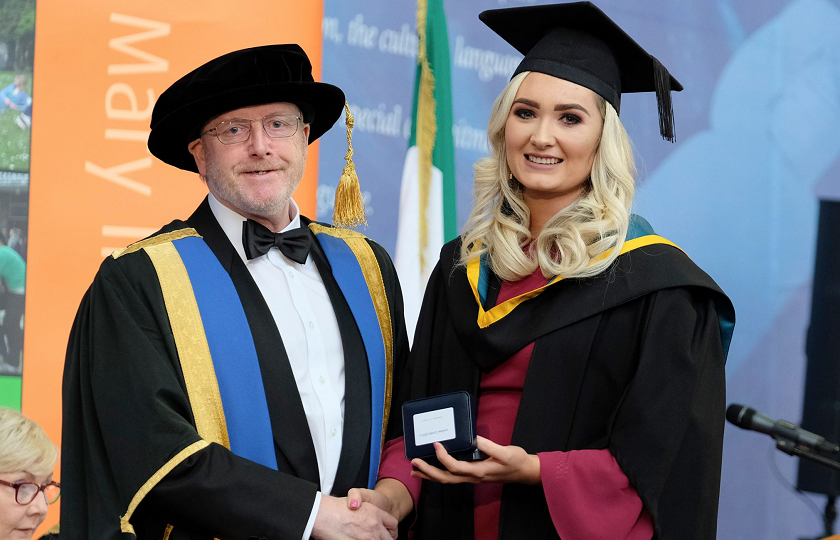 Louise Curtin pictured in her graduation gowns being presented with a medal from Professor Eugene Wall, President of MIC