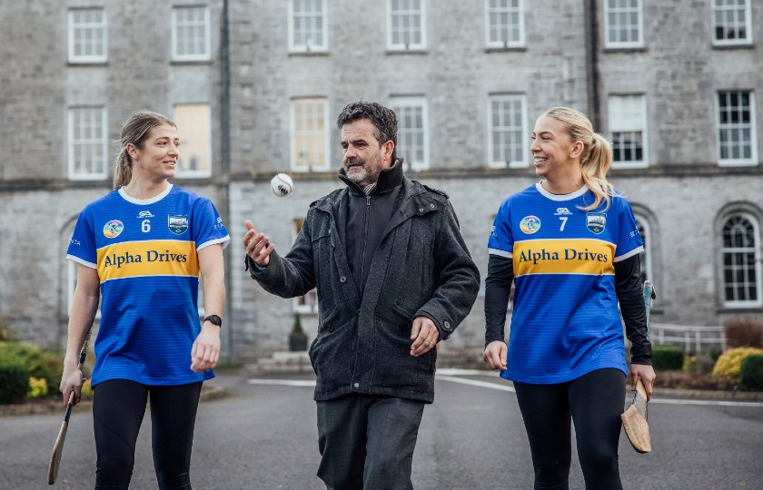 Joint captains Karen Kennedy and Clodagh Quirke walking with Finn O'Murchu who is throwing a sliothar