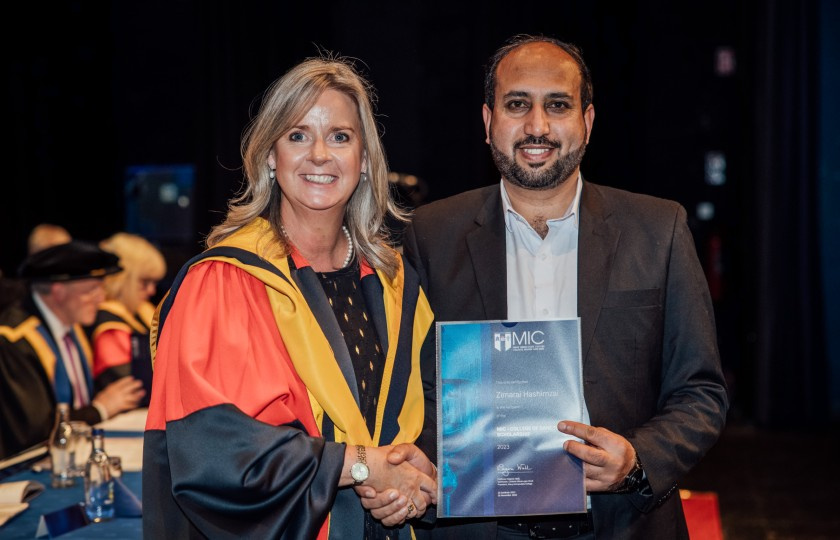 Professor Lorraine McIlrath in ceremonial robes presenting Zimarai with his certificate in recognition of his award