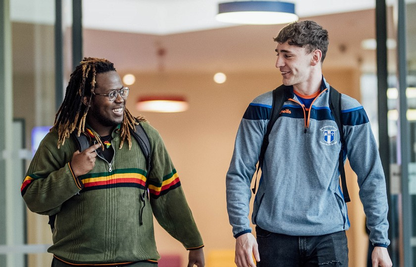 Two male students walking through door and talking to each other