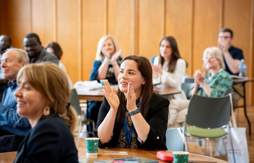 Woman clapping hands at a table in centre of room