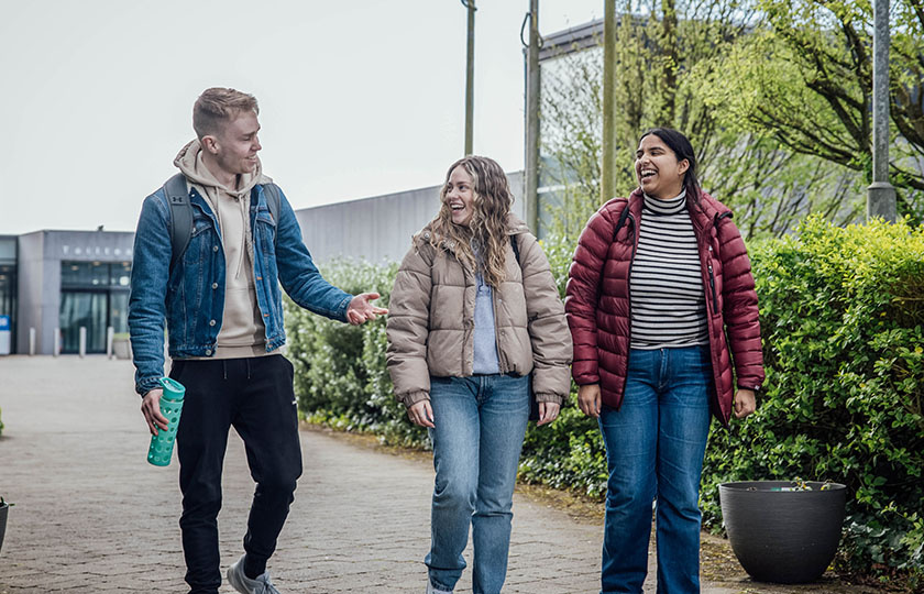 Three undergraduate students walking and chatting on MIC campus