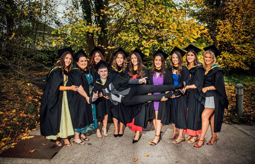 Male graduate being carried by a group of female graduates at MIC Graduation 2024