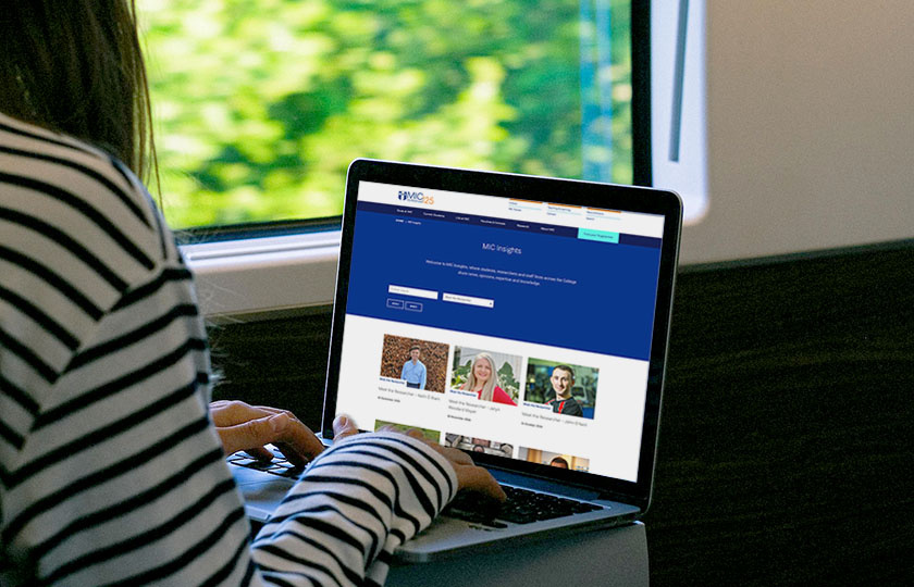 Student sitting at open laptop with MIC Insights blog on screen