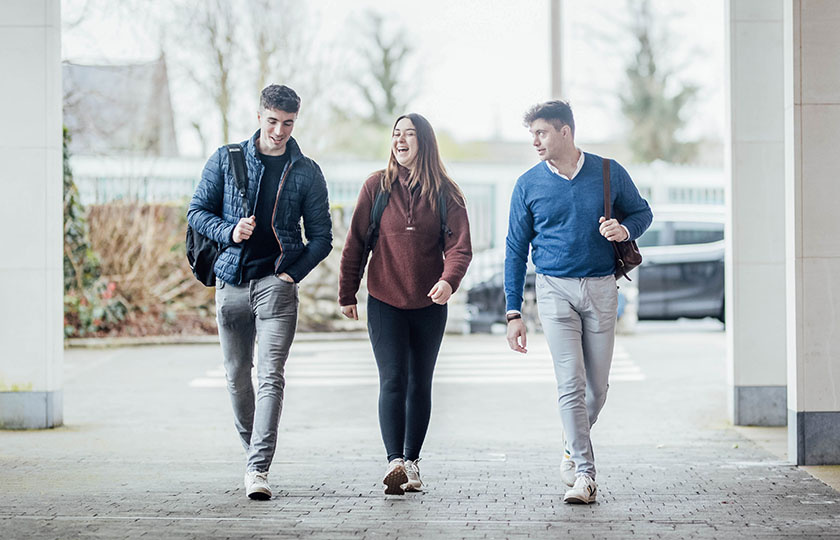 Three postgraduate students walking into the main MIC building