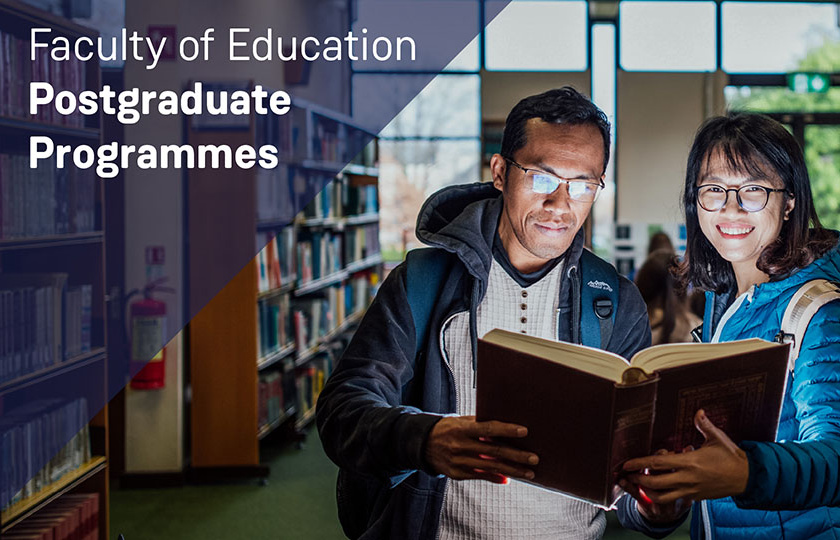 Two postgraduate students looking at a book in MIC's Library