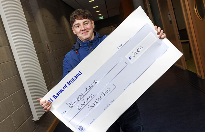 Entrance scholarship recipient holding large cheque