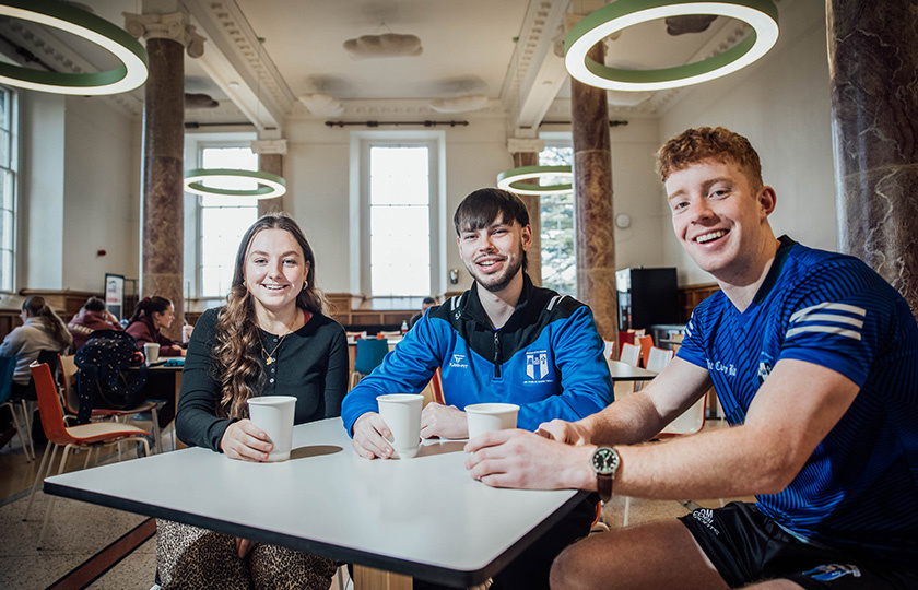 Three students sitting in college canteen.