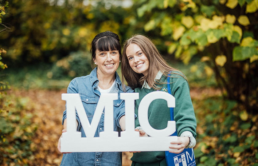 Two women holding a 3D MIC sign.