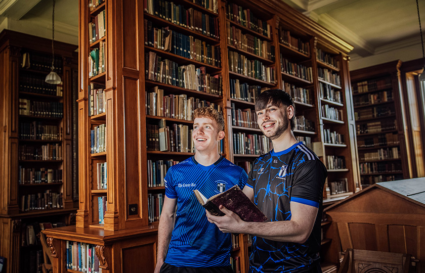 Two students reading a book and admiring the library.