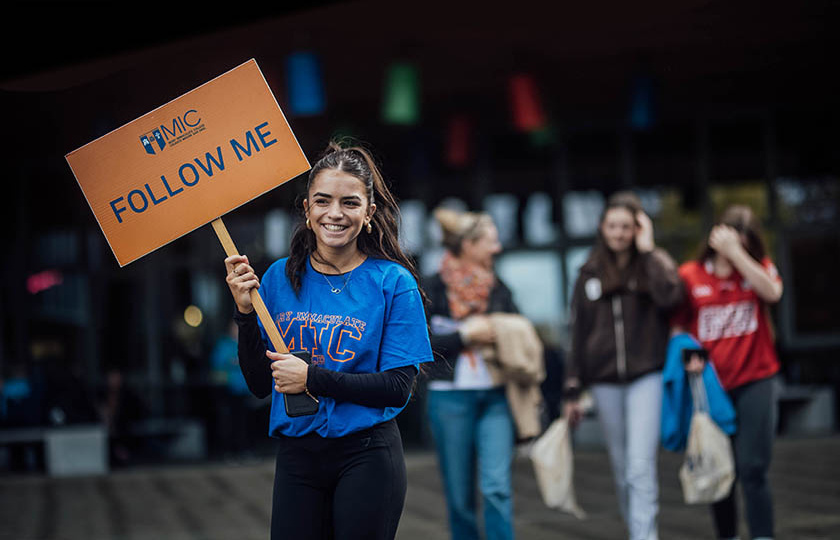 Student holding a Follow me sign on open days at MIC