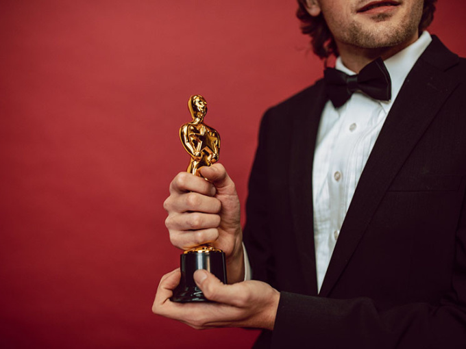 Man wearing tuxedo holding an Oscar statuette