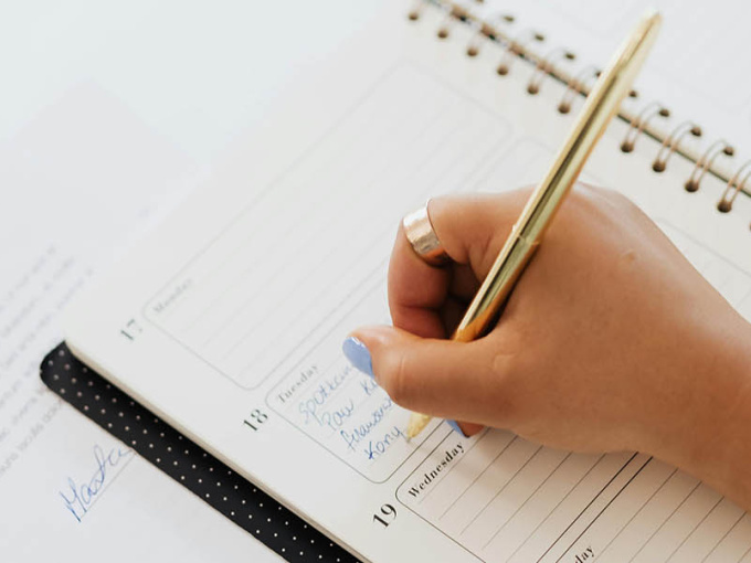 person writing in calendar diary